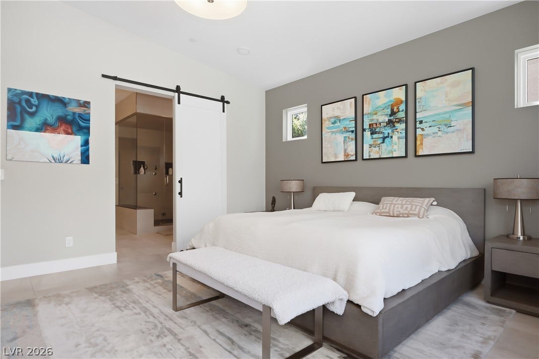 A sliding barn door opens directly from this serene bedroom into an attached bathroom.