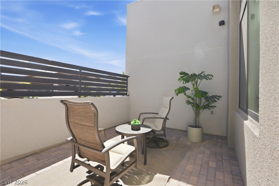 An intimate, paved private patio is enclosed by stucco walls and a modern slat fence.