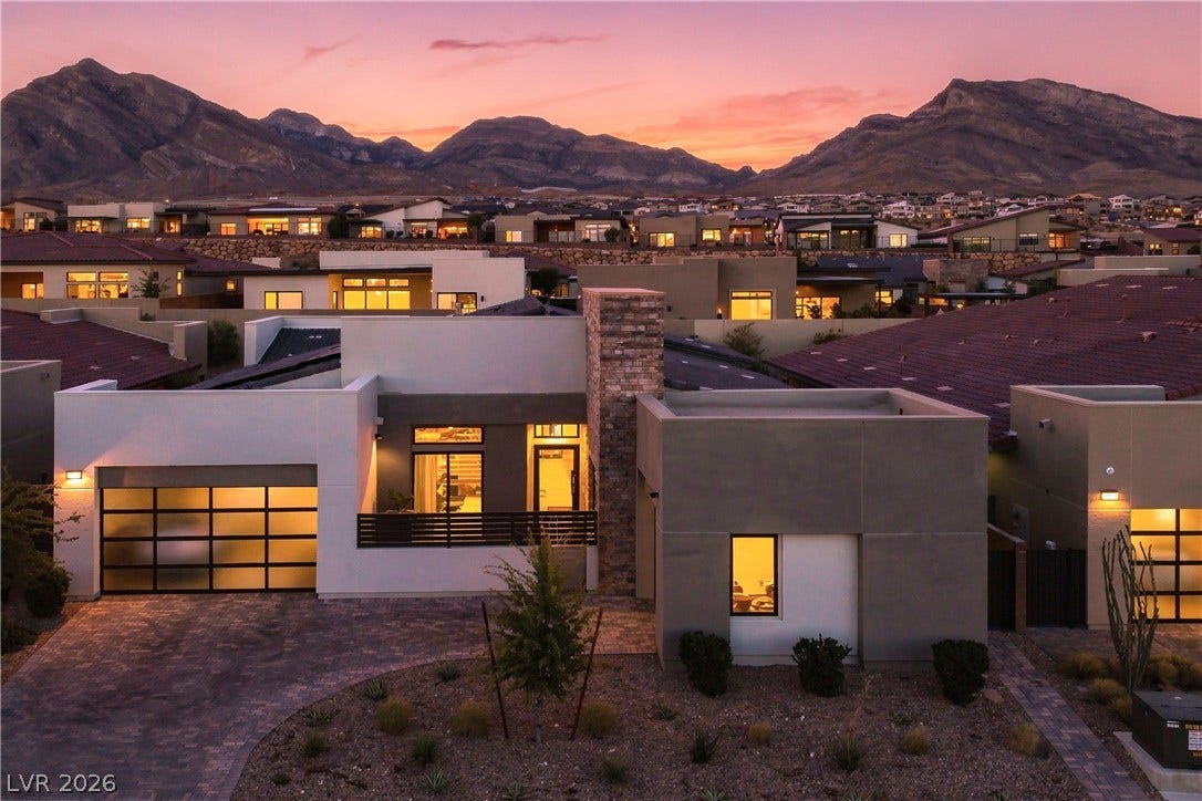 Dramatic mountain peaks frame a striking contemporary home with clean architectural lines.