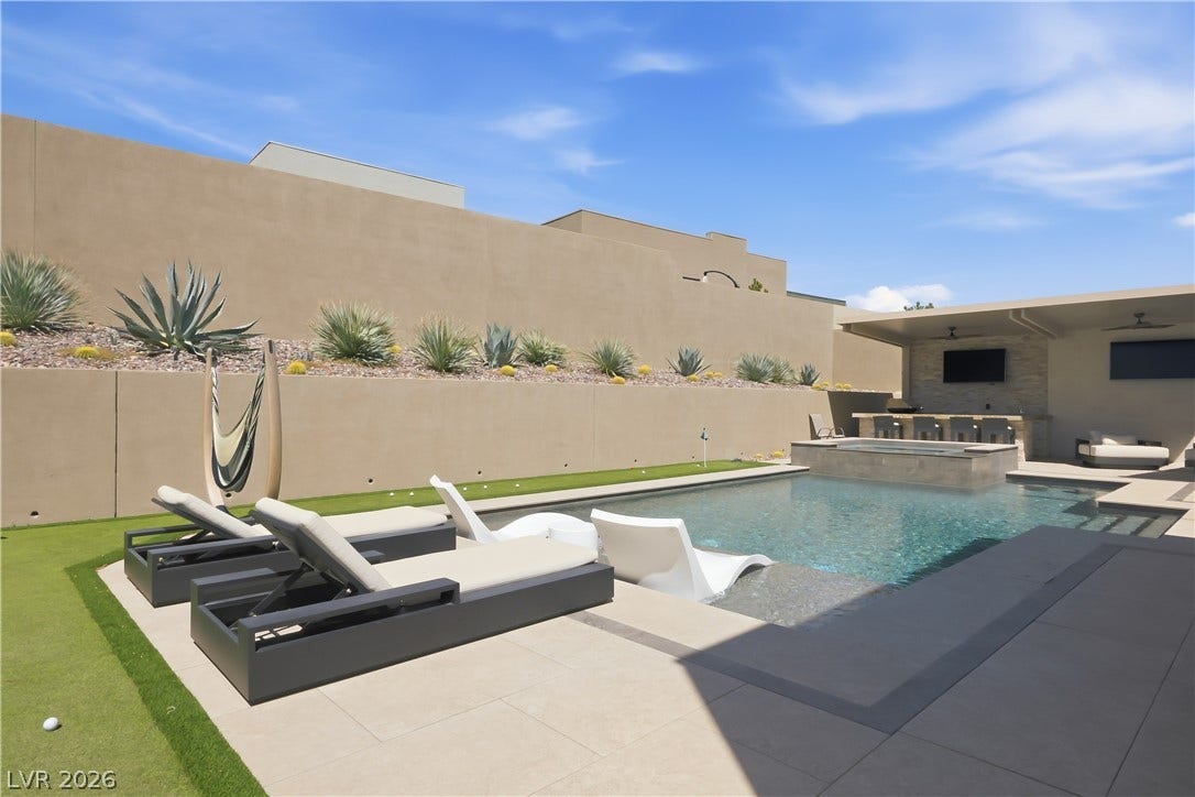 A sparkling in-ground pool is flanked by clean modern hardscaping and minimalist desert plantings.