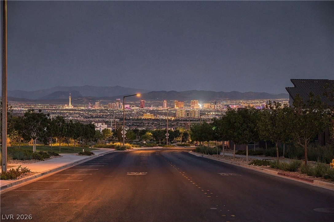 Glimmering city skyline lights pair with mountain silhouettes under the evening sky.