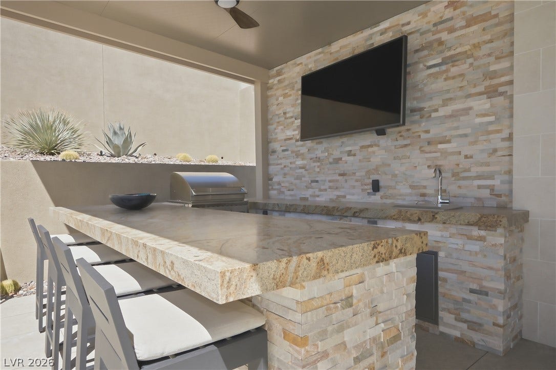 Thick stone countertops elevate this covered outdoor kitchen and bar area.