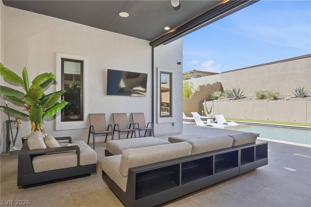 A covered patio with tiled flooring opens directly to the poolside lounge area.