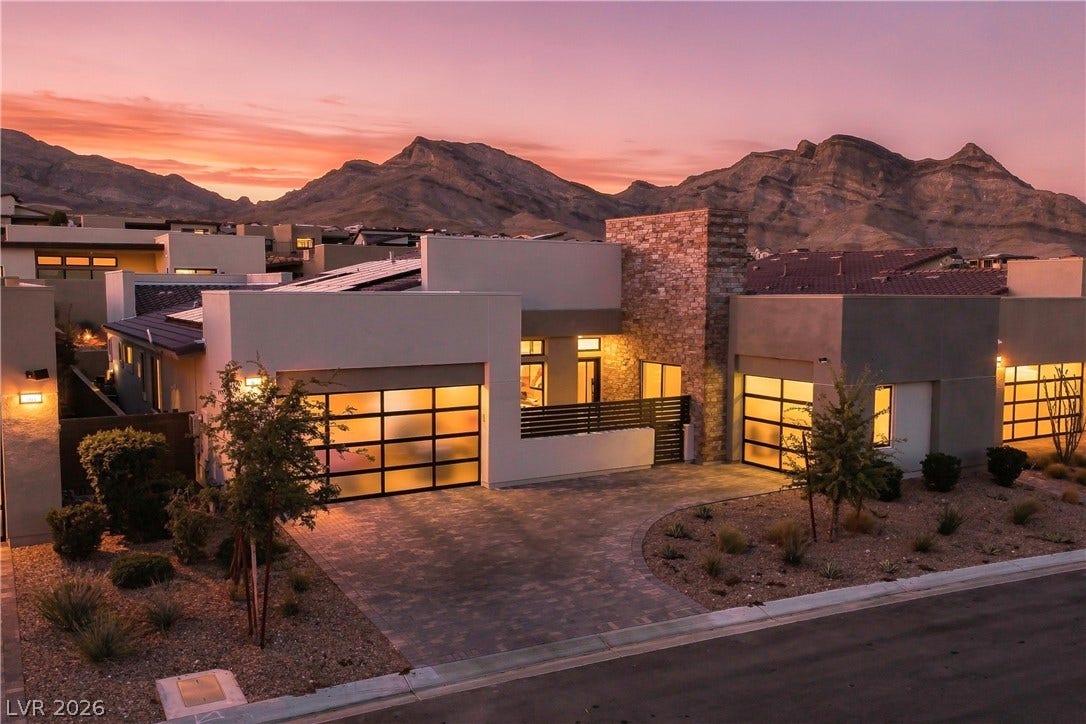 Dramatic mountain backdrops frame this contemporary stone and stucco exterior with sleek glass garage doors.