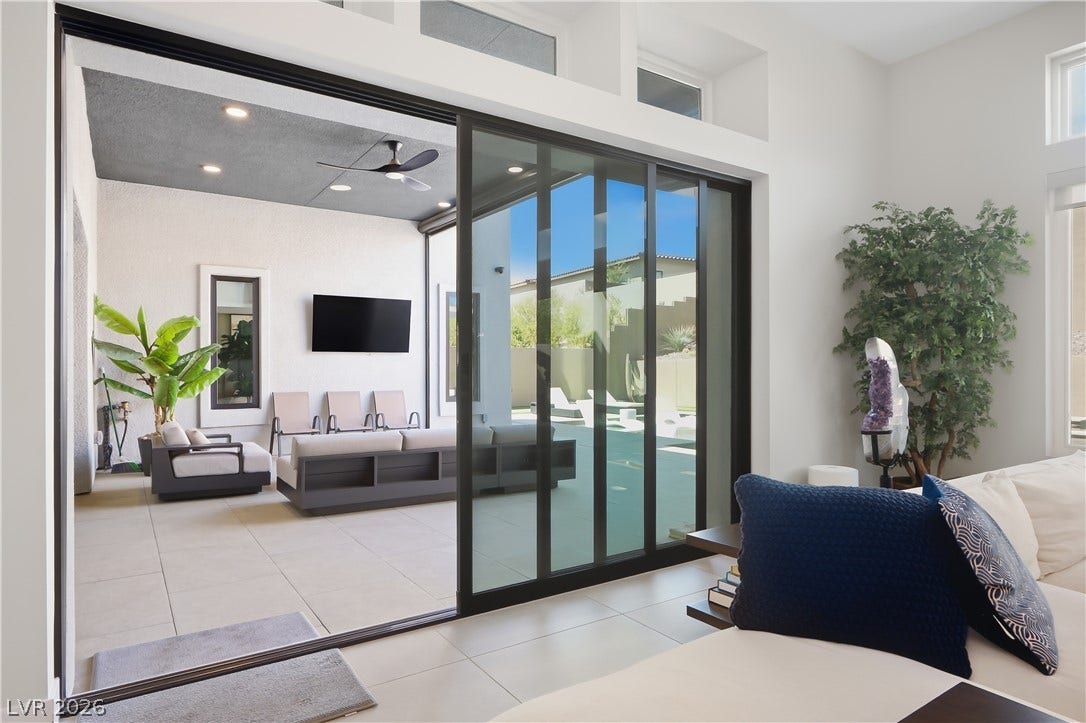 Massive sliding glass doors merge comfortable indoor living spaces with a covered patio.