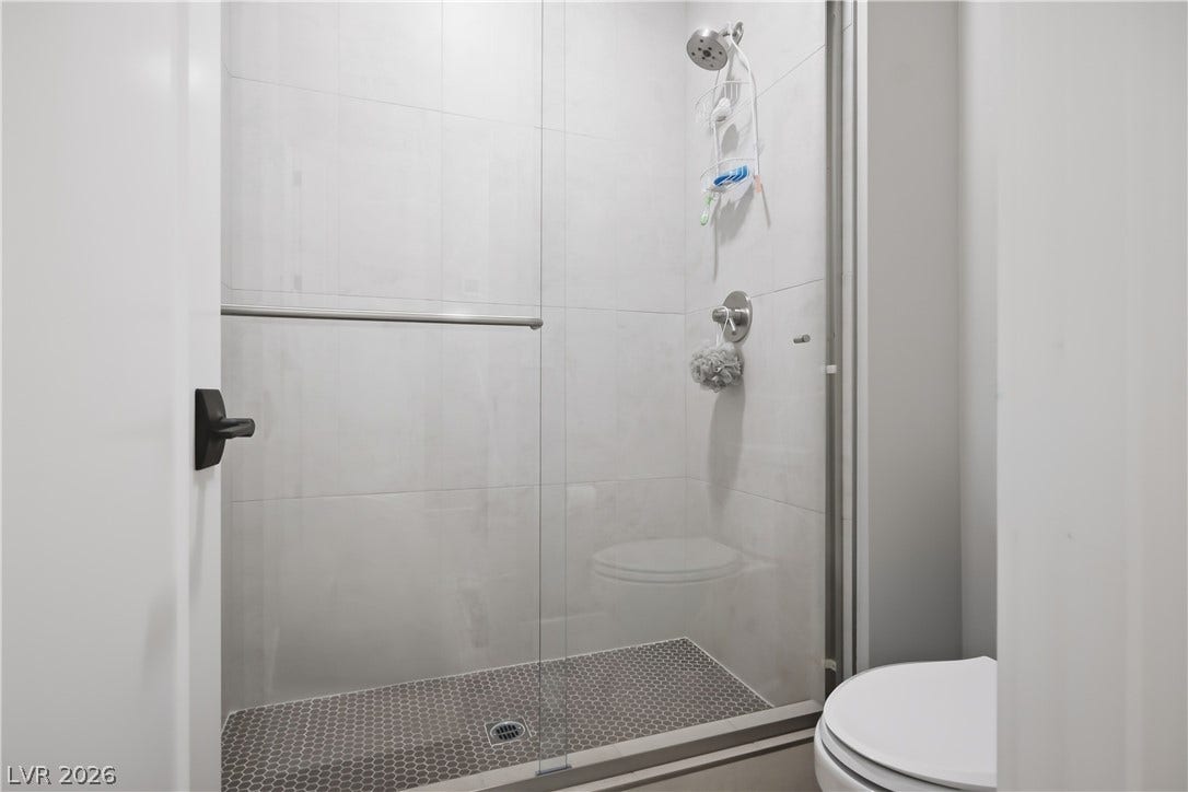 A glass-enclosed walk-in shower features large wall tiles and contrasting penny floor tiles.