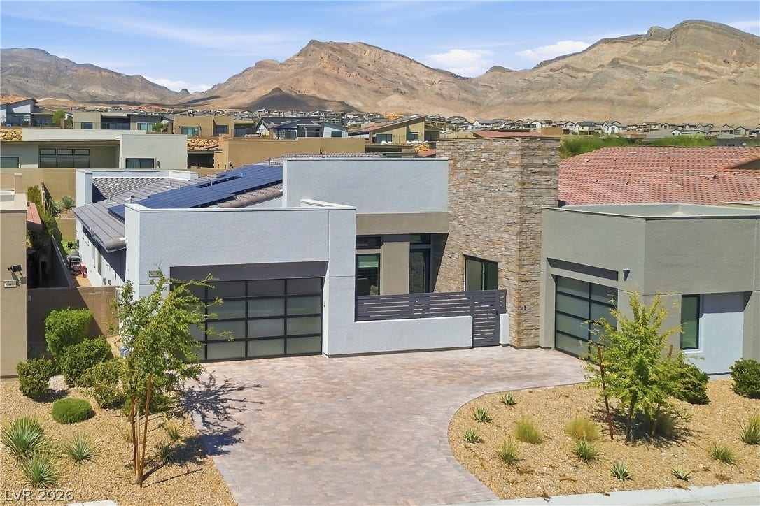 Dramatic mountain peaks frame this modern exterior complete with stone accents and a paved driveway.