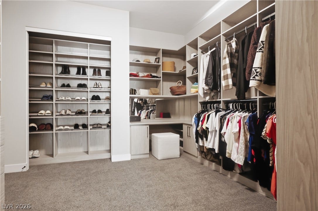 Custom built-in shelving and soft carpeting define this spacious dressing area.