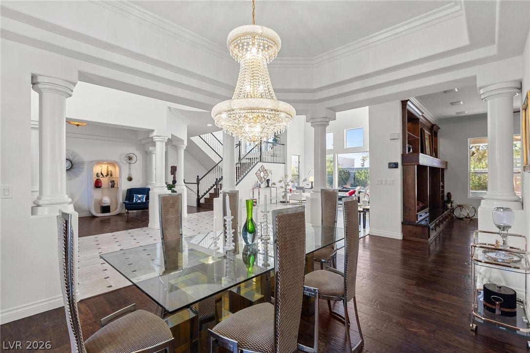 8088 Dark Hollow Place, Las Vegas, NV 89117 Elegant dining area featuring a glass table beneath a grand chandelier, flowing into an open-concept living space.