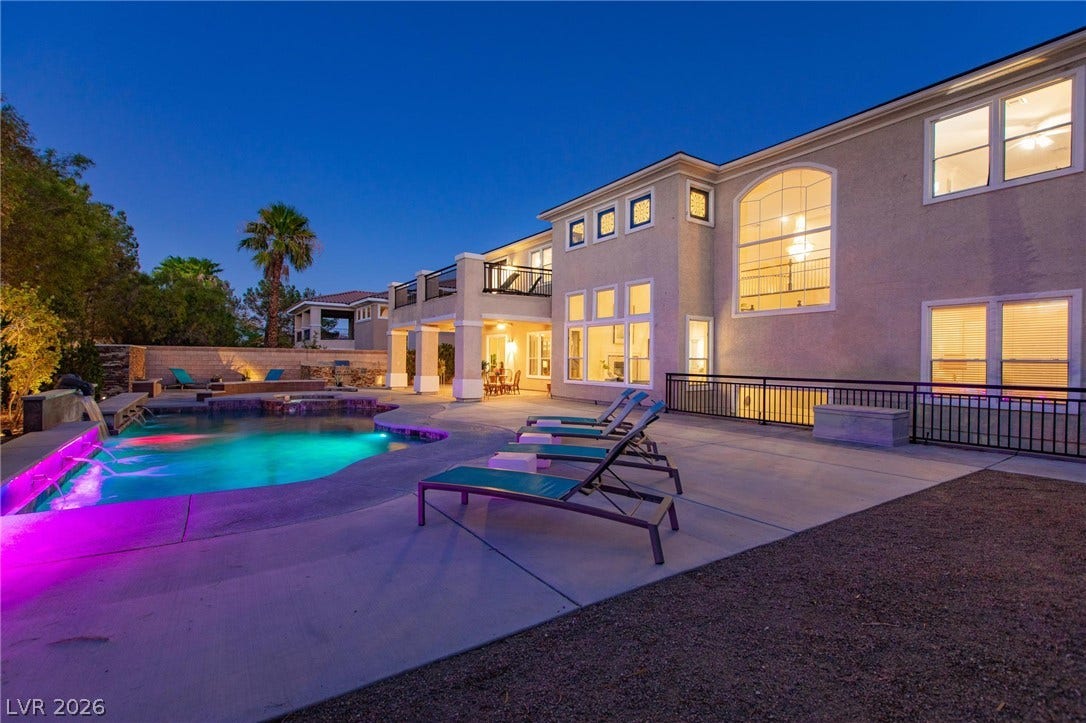 8088 Dark Hollow Place, Las Vegas, NV 89117 An illuminated pool with vibrant lighting creates a nighttime oasis beside this grand residence.