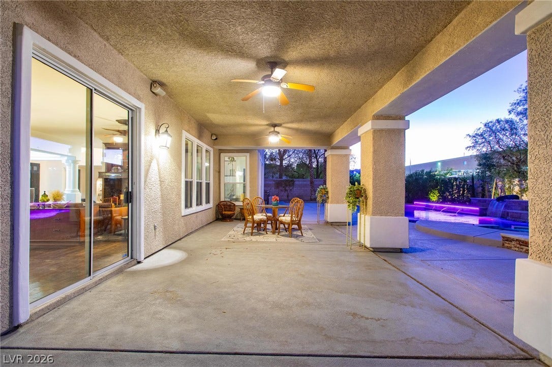 8088 Dark Hollow Place, Las Vegas, NV 89117 A spacious covered patio offers ample room for dining and relaxation, overlooking a vibrant, illuminated pool.