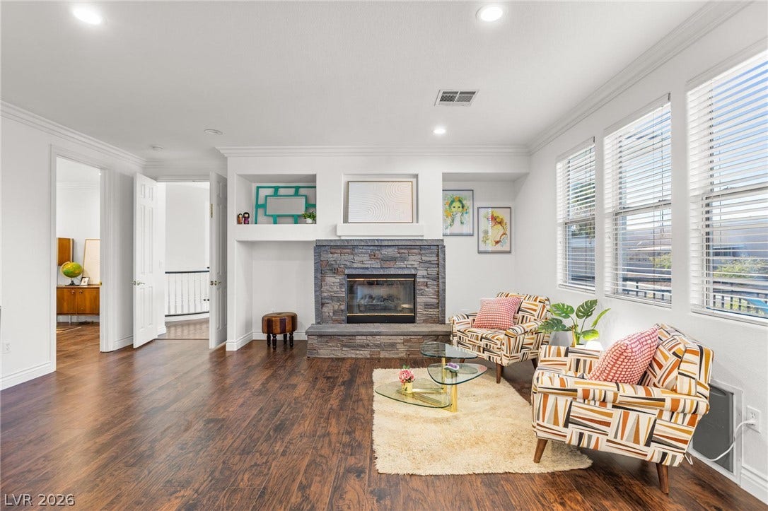 8088 Dark Hollow Place, Las Vegas, NV 89117 A well-lit living space features rich hardwood flooring and a prominent stone fireplace, perfect for gathering.