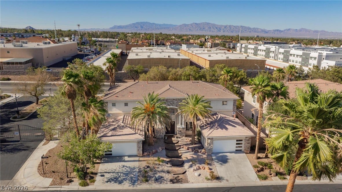 8088 Dark Hollow Place, Las Vegas, NV 89117 An aerial perspective reveals this grand residence, showcasing its dual garages and welcoming palm-lined entry.
