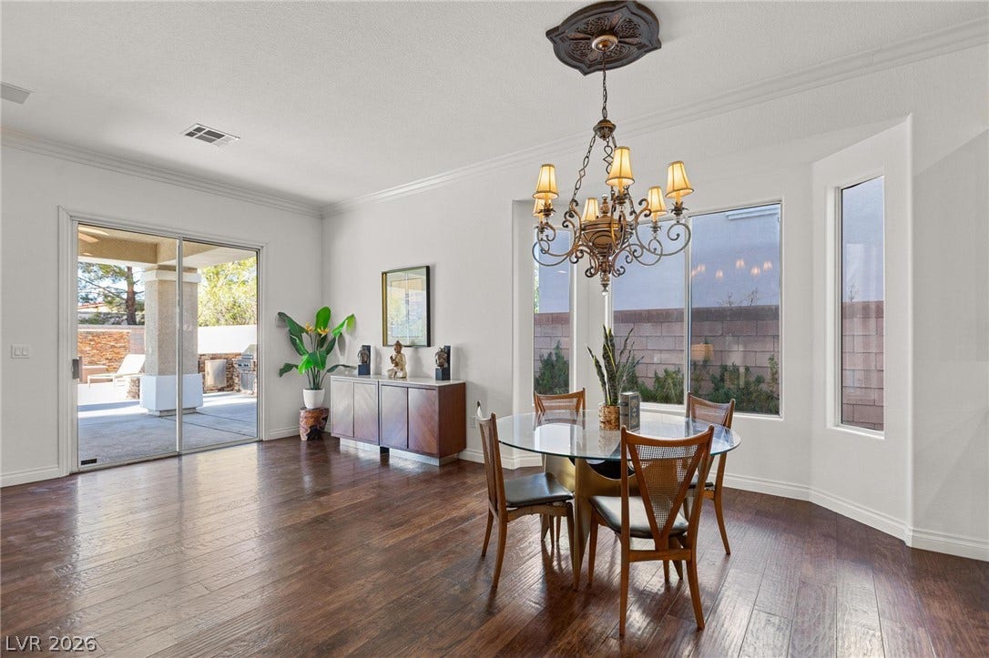 8088 Dark Hollow Place, Las Vegas, NV 89117 Ornate chandelier and hardwood flooring grace this elegant dining area with an inviting patio view.