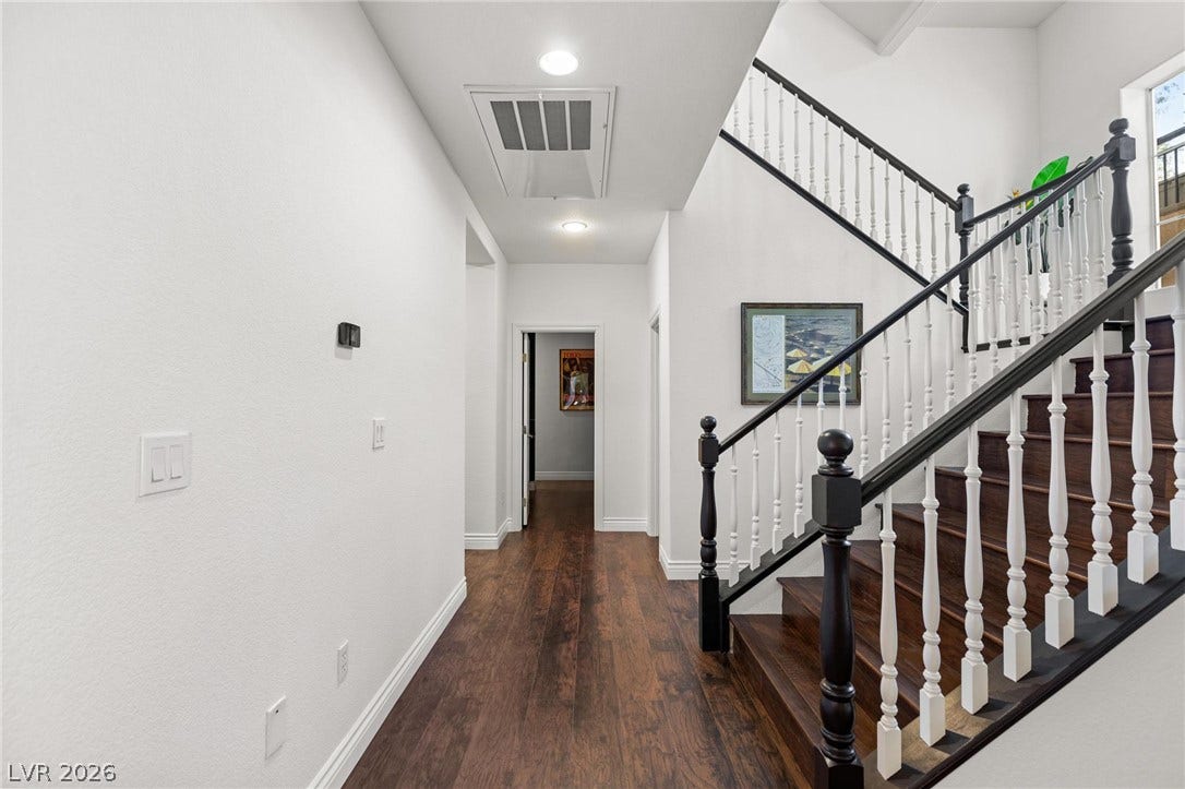 8088 Dark Hollow Place, Las Vegas, NV 89117 Elegant dark wood flooring extends through the well-lit hallway and up the stately staircase.