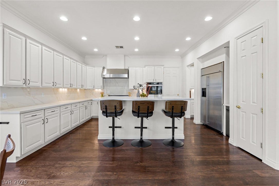 8088 Dark Hollow Place, Las Vegas, NV 89117 A chef's dream kitchen features rich hardwood flooring, pristine white cabinetry, and recessed lighting.