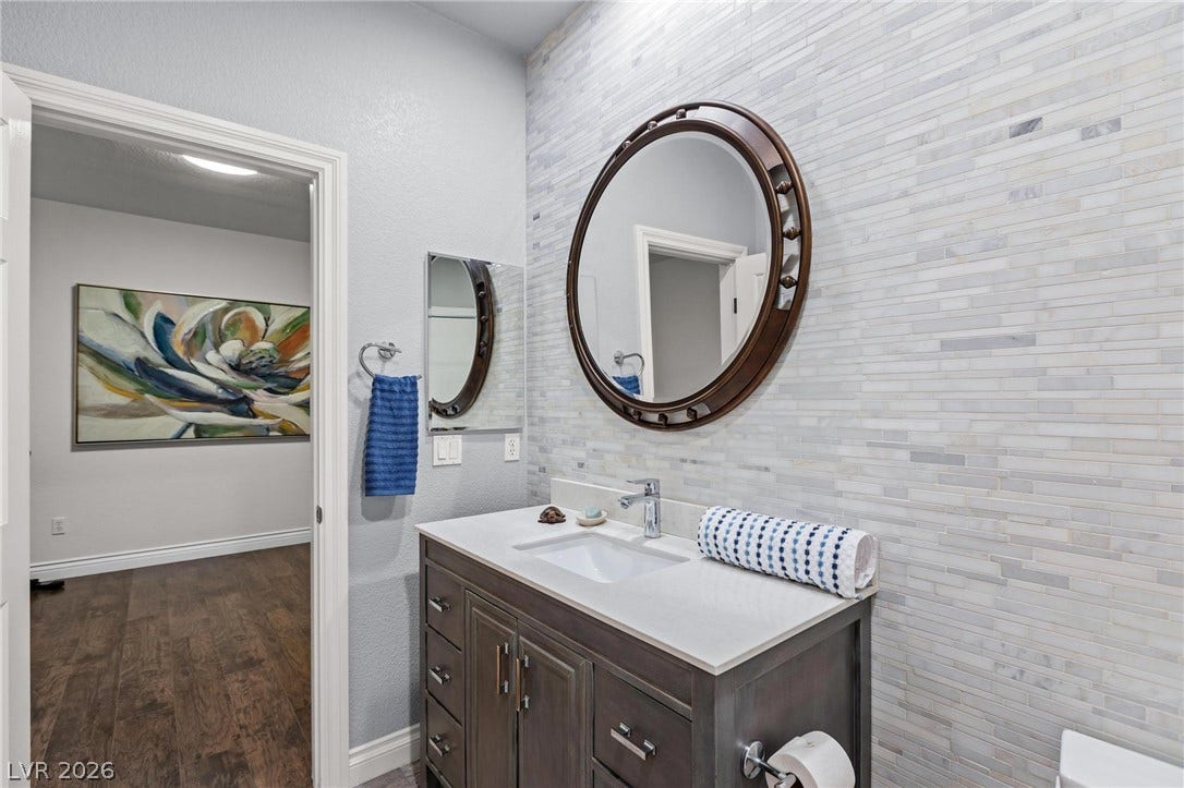 8088 Dark Hollow Place, Las Vegas, NV 89117 A well-appointed bathroom features a sleek vanity, stylish mirrors, and elegant tiled accent wall.
