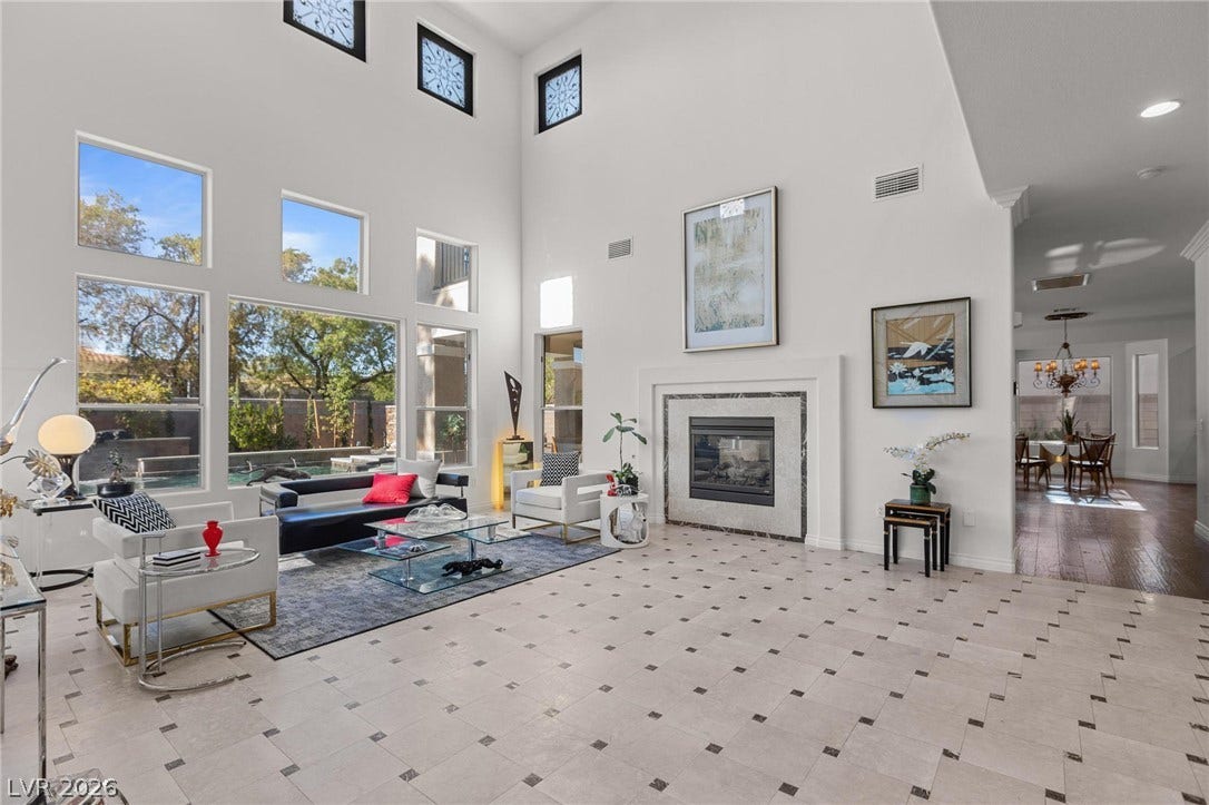 8088 Dark Hollow Place, Las Vegas, NV 89117 A spacious, naturally illuminated family room presents high ceilings, a grand fireplace, and polished tile flooring.