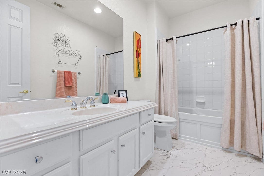 8088 Dark Hollow Place, Las Vegas, NV 89117 White cabinetry with a polished countertop offers a clean aesthetic in this well-appointed bath.