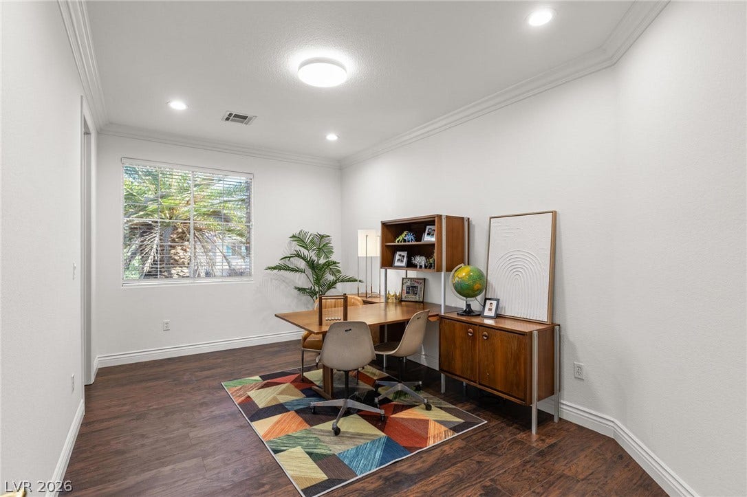 8088 Dark Hollow Place, Las Vegas, NV 89117 A well-lit room connected to the primary bedroom features rich hardwood flooring and a bright window overlooking lush greenery.