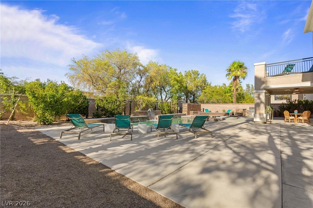 8088 Dark Hollow Place, Las Vegas, NV 89117 An inviting backyard oasis offers a sparkling pool with a tranquil waterfall and an outdoor entertaining area.