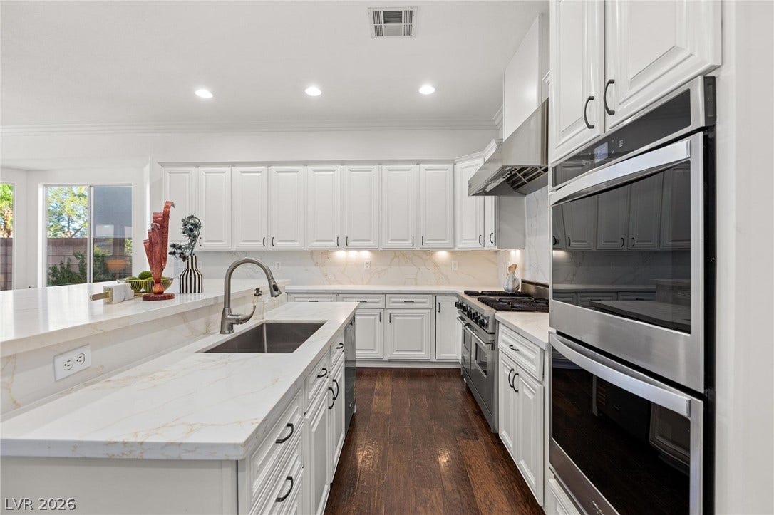 8088 Dark Hollow Place, Las Vegas, NV 89117 A chef's kitchen showcasing white shaker cabinets and sleek stainless steel appliances.