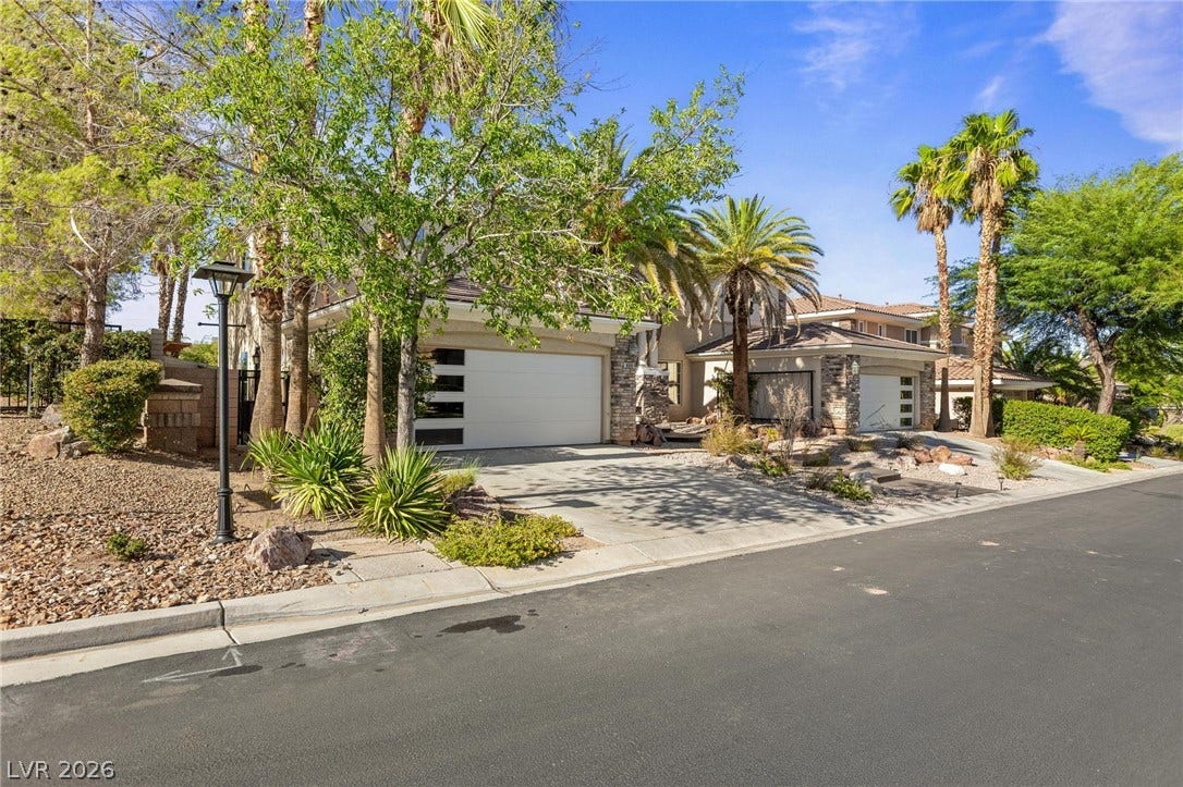 8088 Dark Hollow Place, Las Vegas, NV 89117 A well-appointed residence offers a spacious driveway and attached garage, nestled amidst a verdant landscape.