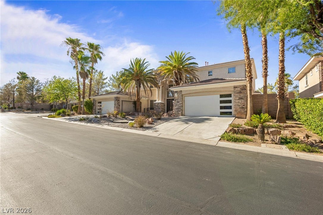 8088 Dark Hollow Place, Las Vegas, NV 89117 A desert-modern residence with striking stone accents and mature palm trees defining its grand facade.