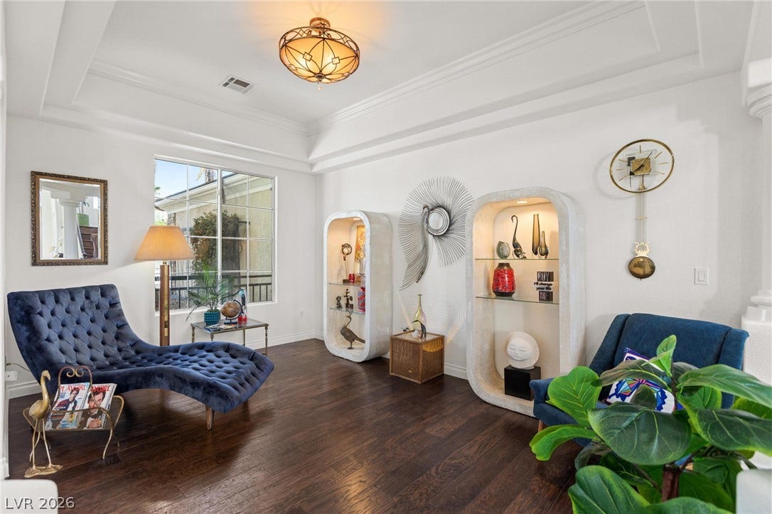 8088 Dark Hollow Place, Las Vegas, NV 89117 Rich hardwood flooring complements the deep blue chaise lounge and decorative shelving, set against a backdrop of natural light.