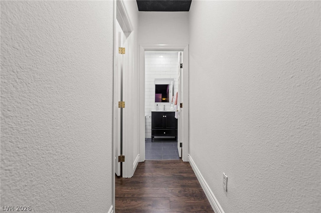 8088 Dark Hollow Place, Las Vegas, NV 89117 Rich hardwood floors guide you toward the inviting bathroom, accented by a contrasting dark vanity.