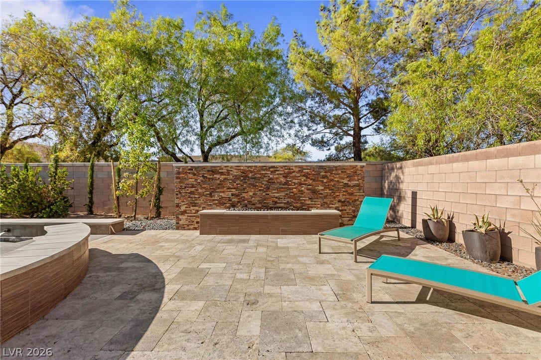 8088 Dark Hollow Place, Las Vegas, NV 89117 An inviting backyard oasis offers a built-in fire pit and ample paver patio space for relaxation.