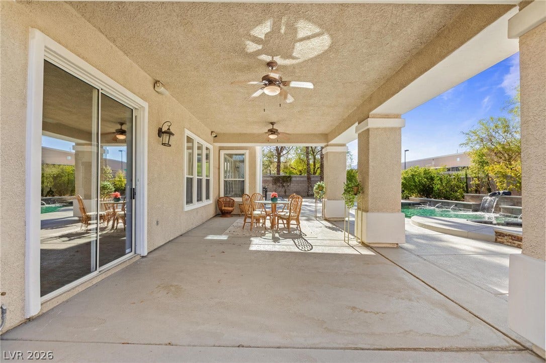 8088 Dark Hollow Place, Las Vegas, NV 89117 An inviting covered patio with ceiling fans extends to a private pool and spa, perfect for outdoor living.