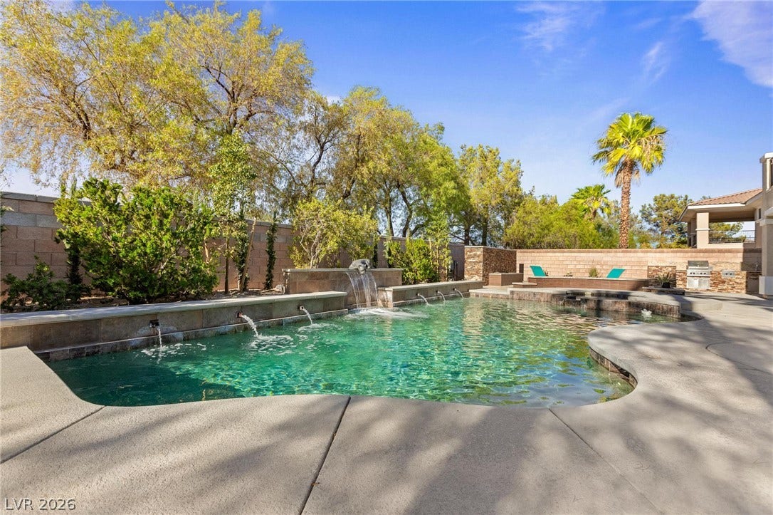 8088 Dark Hollow Place, Las Vegas, NV 89117 An inviting backyard oasis features a shimmering pool with integrated waterfalls and a built-in outdoor grill.