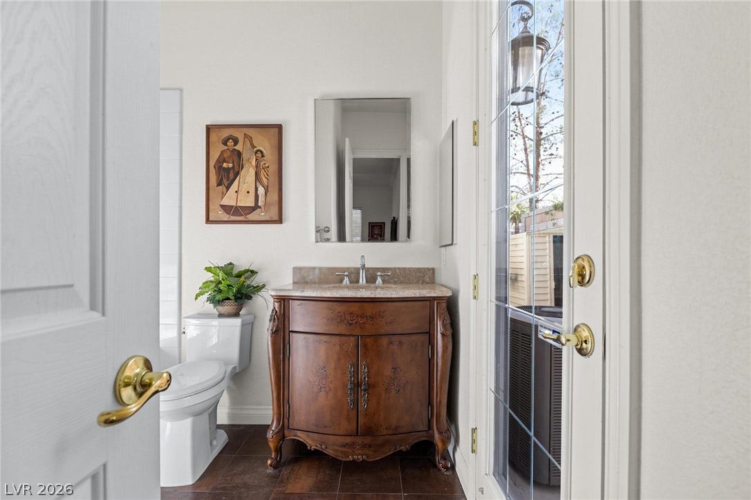 8088 Dark Hollow Place, Las Vegas, NV 89117 The bathroom features an ornate vanity with a stone countertop and rich wood flooring.