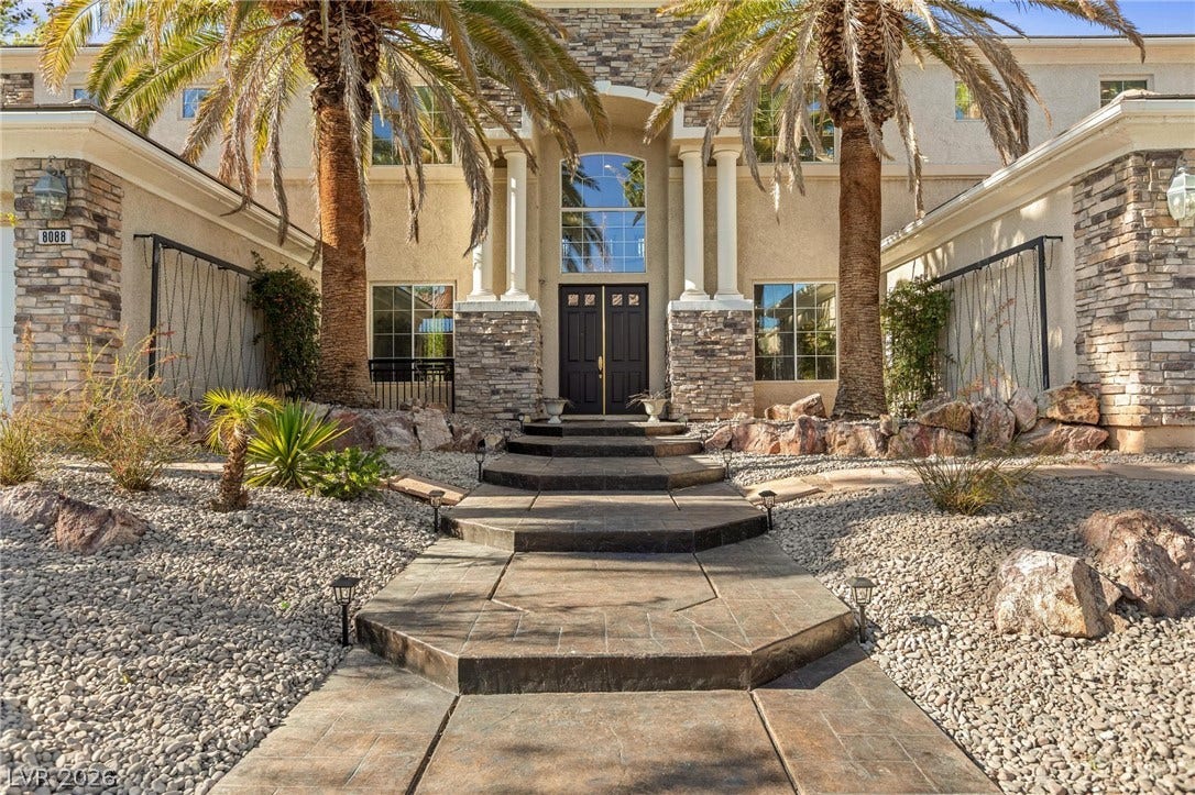 8088 Dark Hollow Place, Las Vegas, NV 89117 A grand entryway features towering columns, decorative stone accents, and a tiered walkway leading to the front door.