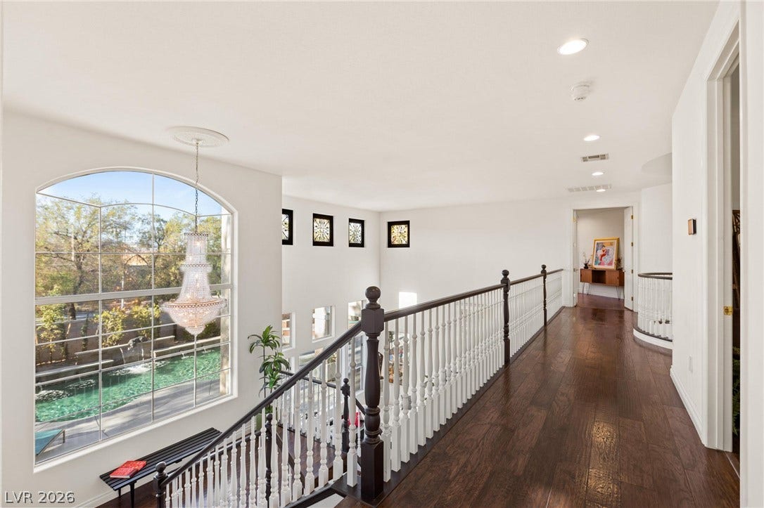 8088 Dark Hollow Place, Las Vegas, NV 89117 A grand arched window in this upper-level hallway showcases a sparkling pool and lush landscaping.