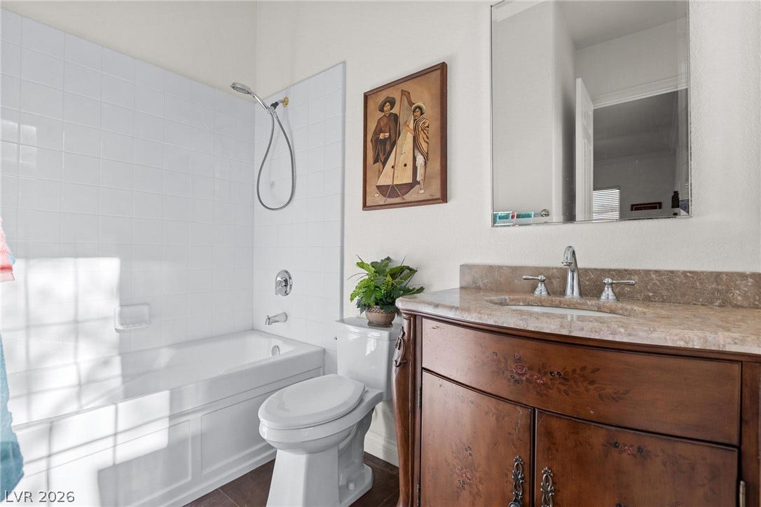 8088 Dark Hollow Place, Las Vegas, NV 89117 The bathroom features a marble-topped vanity and a clean, tiled shower-tub combination.