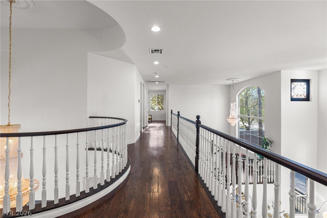 8088 Dark Hollow Place, Las Vegas, NV 89117 Elegant hardwood flooring extends through the bright upper-level hallway, illuminated by recessed lighting and a sophisticated chandelier.