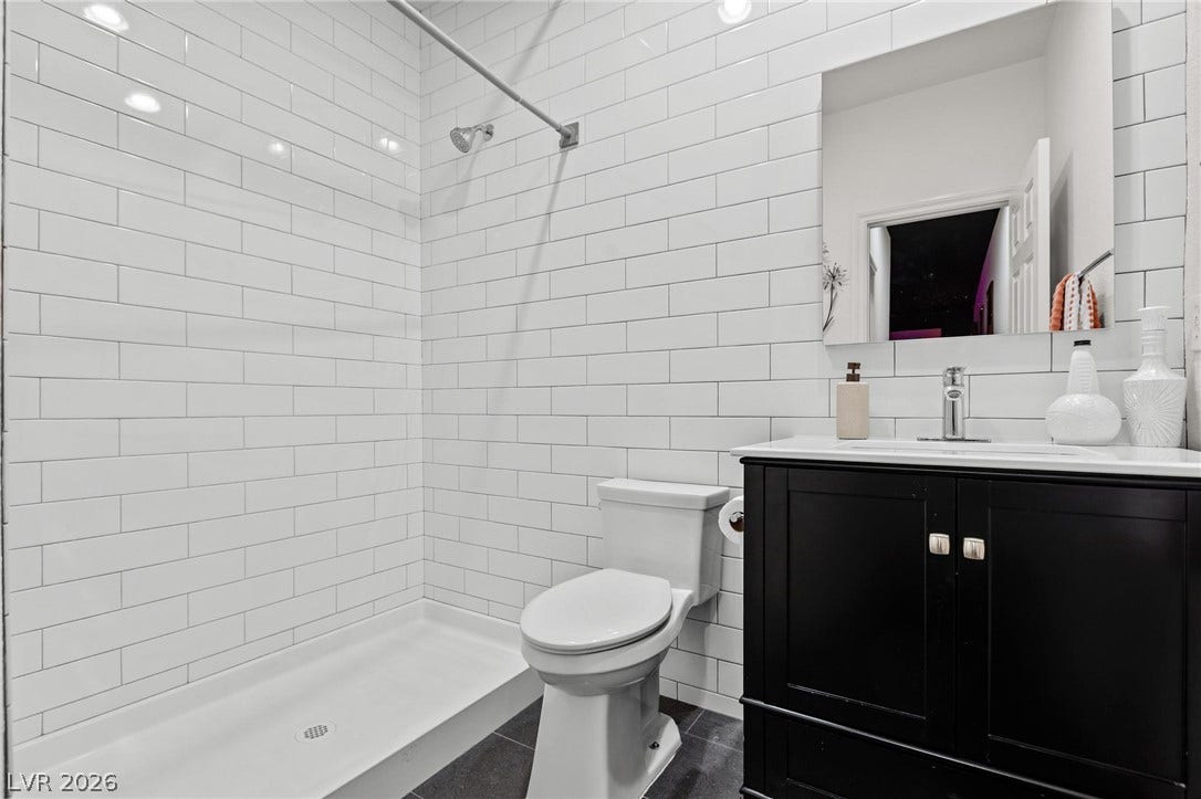 8088 Dark Hollow Place, Las Vegas, NV 89117 A well-appointed bath features a tiled shower with a sleek glass enclosure and a stylish vanity with ample storage.