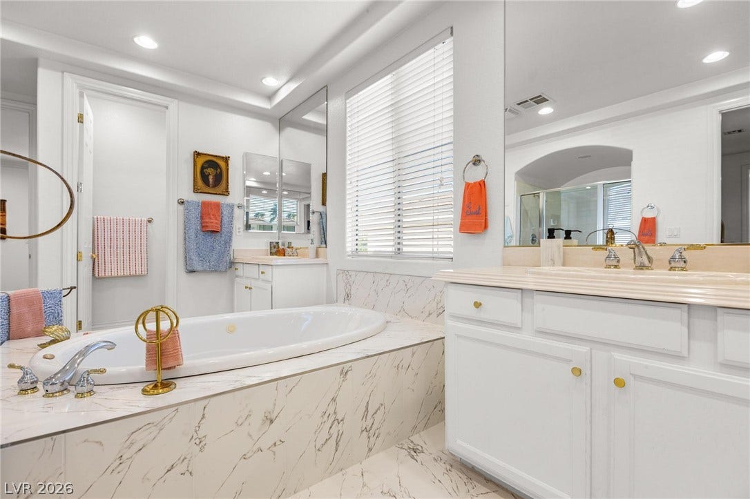 8088 Dark Hollow Place, Las Vegas, NV 89117 Indulge in a pristine primary bathroom, featuring a deep soaking tub and elegant marble-look finishes.