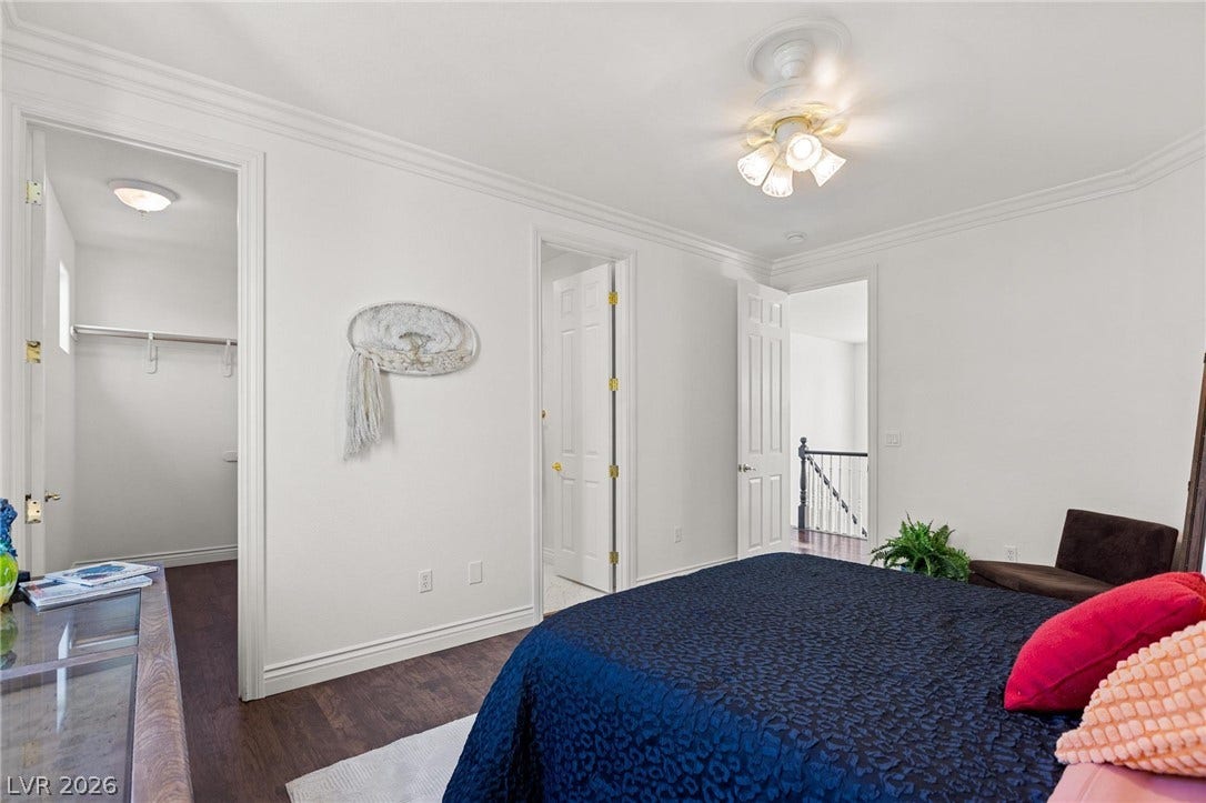 8088 Dark Hollow Place, Las Vegas, NV 89117 A comfortable bedroom featuring rich wood flooring and crown molding, creating a polished and inviting retreat.