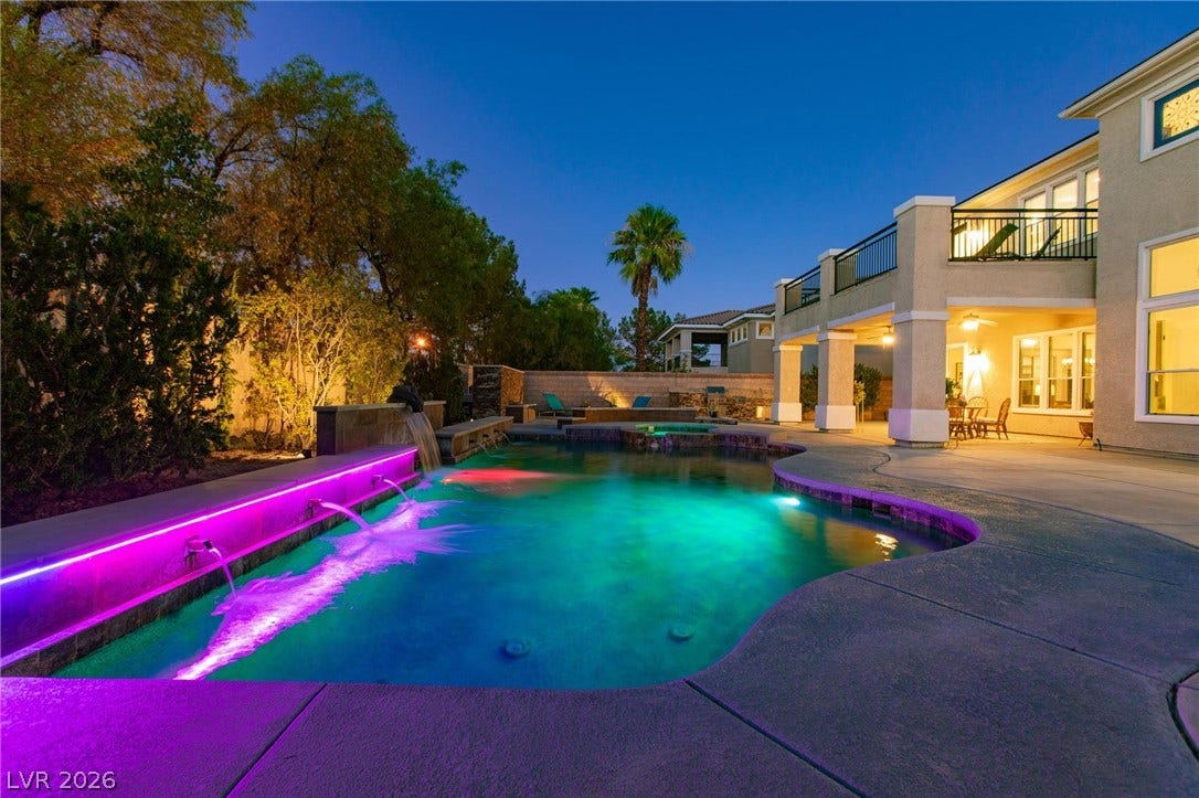 8088 Dark Hollow Place, Las Vegas, NV 89117 An illuminated backyard oasis boasts a sparkling pool with water features and ample patio space for evening enjoyment.