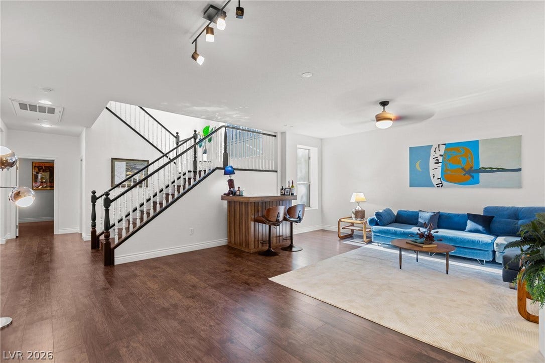 8088 Dark Hollow Place, Las Vegas, NV 89117 Elegant hardwood flooring flows through this open basement, featuring a convenient bar beneath the classic staircase.
