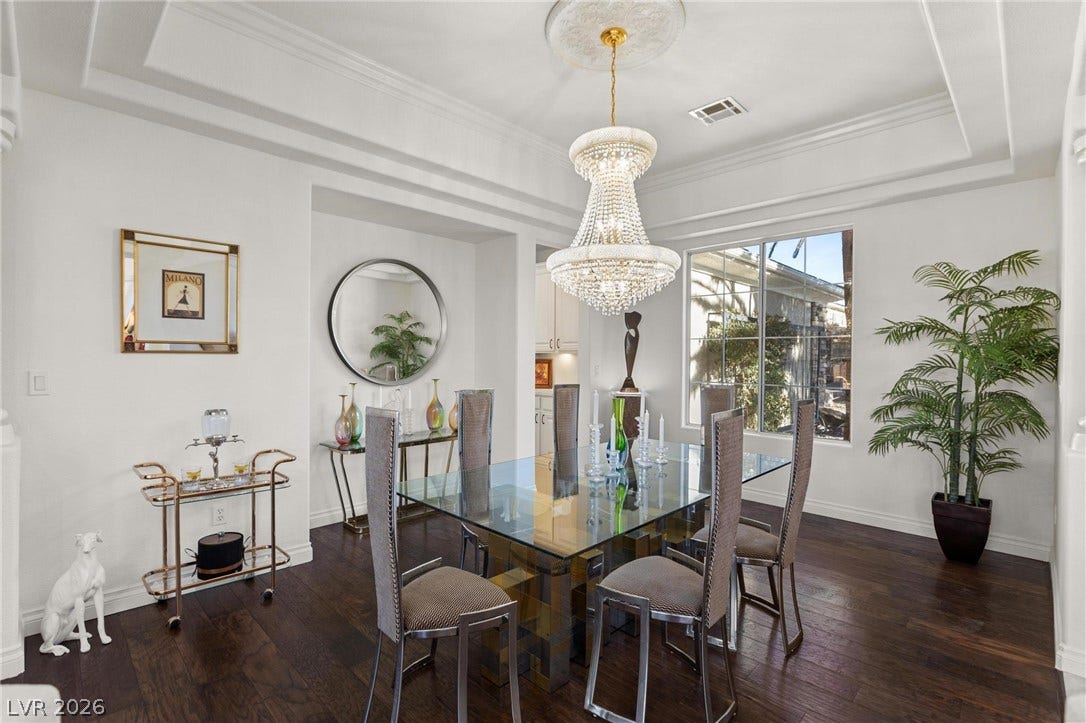 8088 Dark Hollow Place, Las Vegas, NV 89117 A dazzling chandelier illuminates a sophisticated dining space with rich hardwood floors and an elegant glass-top table.