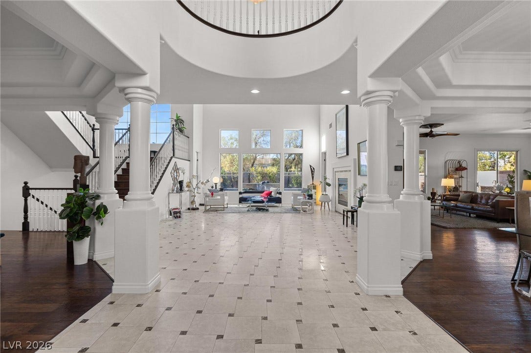 8088 Dark Hollow Place, Las Vegas, NV 89117 Grand two-story foyer featuring elegant columns, a graceful curved staircase, and an inviting view into a naturally illuminated living area.