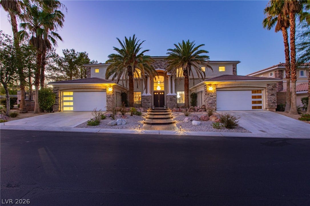 8088 Dark Hollow Place, Las Vegas, NV 89117 A grand faade featuring twin garages and an inviting entryway with elegant stonework and mature palms.