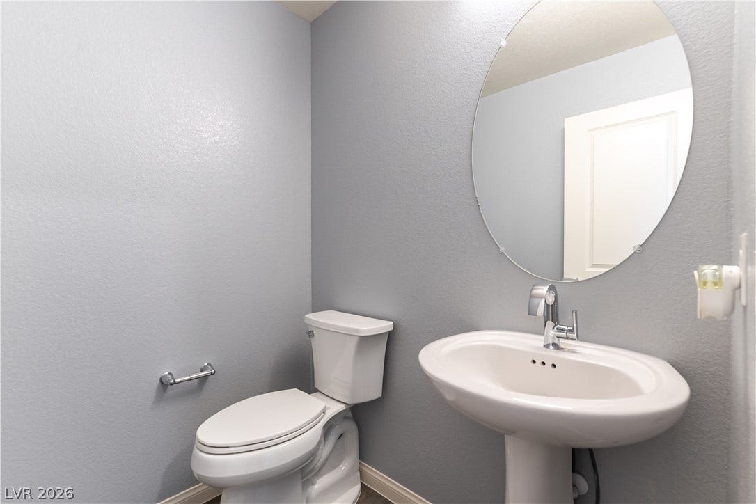 6911 Orange Horizon Street, North Las Vegas, NV 89086 A minimalist pedestal sink and oval mirror anchor this modern powder room.