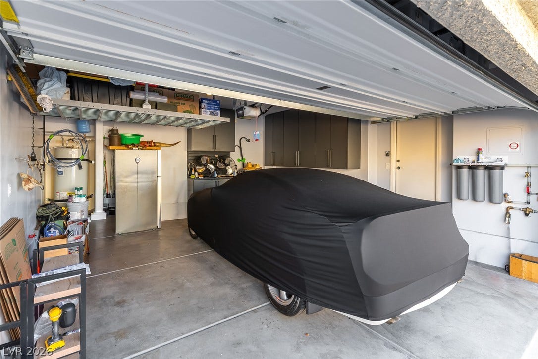 6911 Orange Horizon Street, North Las Vegas, NV 89086 An organized concrete floor garage features built-in cabinets and overhead storage racks.