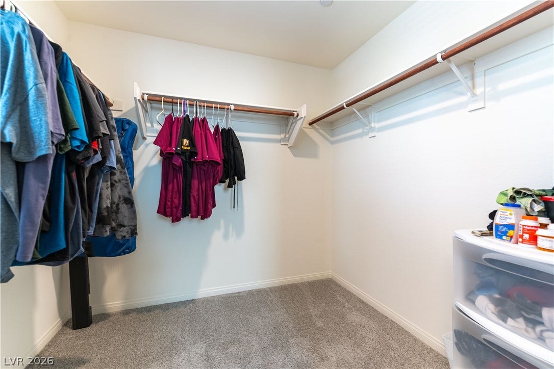 6911 Orange Horizon Street, North Las Vegas, NV 89086 Ample hanging space and neutral carpeting define this functional walk-in closet.