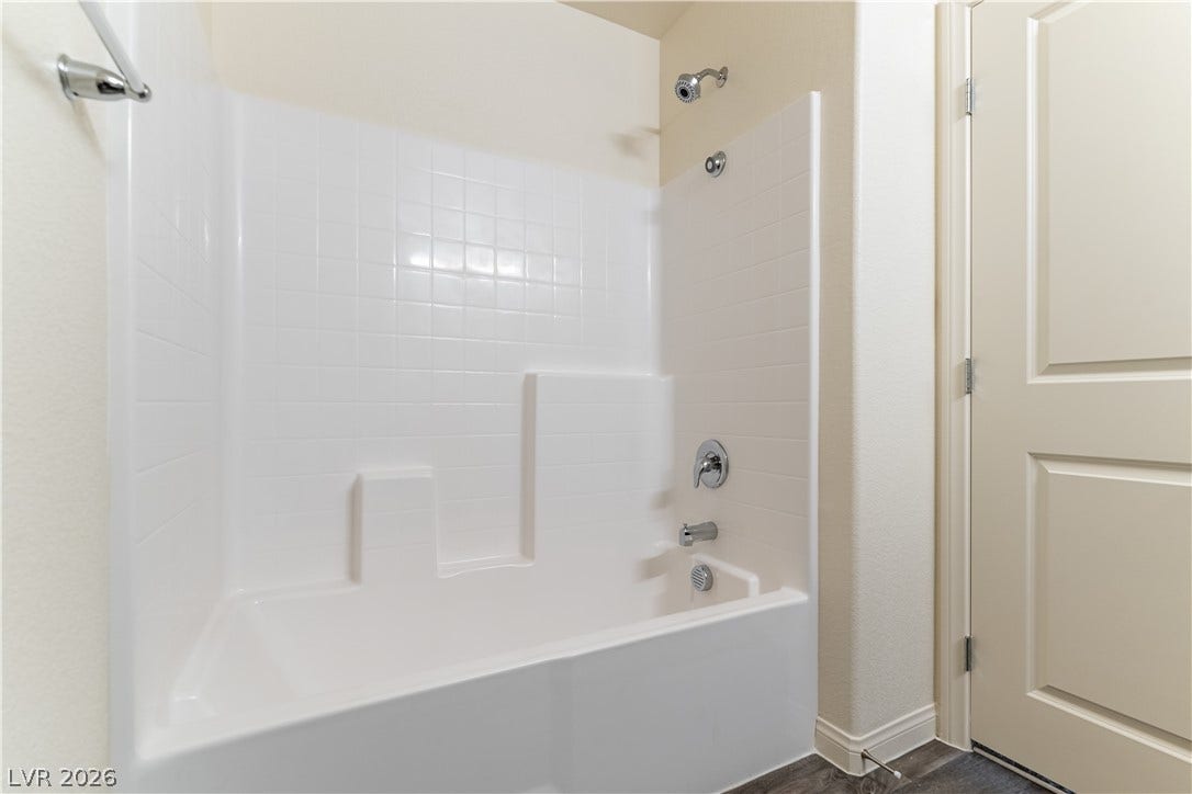 6911 Orange Horizon Street, North Las Vegas, NV 89086 A classic bathtub and shower combination features simple white tile surrounds.